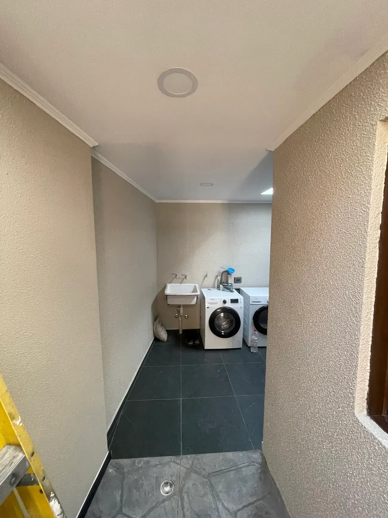 Logia terminada con piso de porcelanato, muros revestidos y lavadora